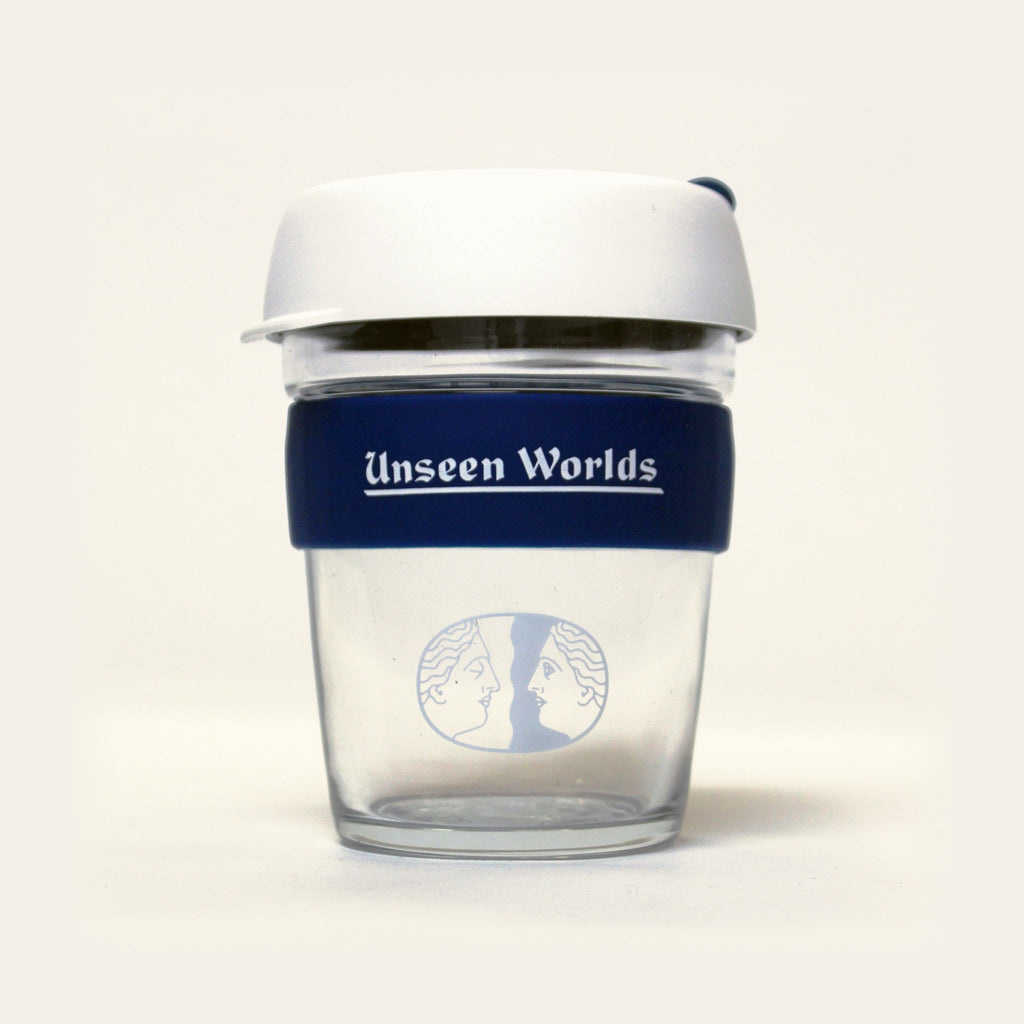 Unseen Worlds glass KeepCup with white lid, navy band with the wordmark and the twin-face logo, front view