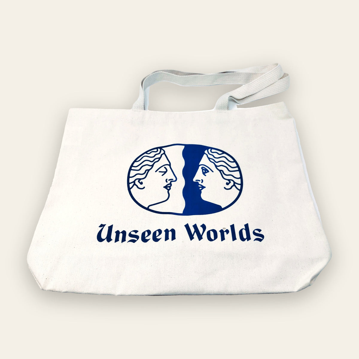 Natural canvas Unseen Worlds logo tote bag with the twin-face logo and wordmark printed in blue