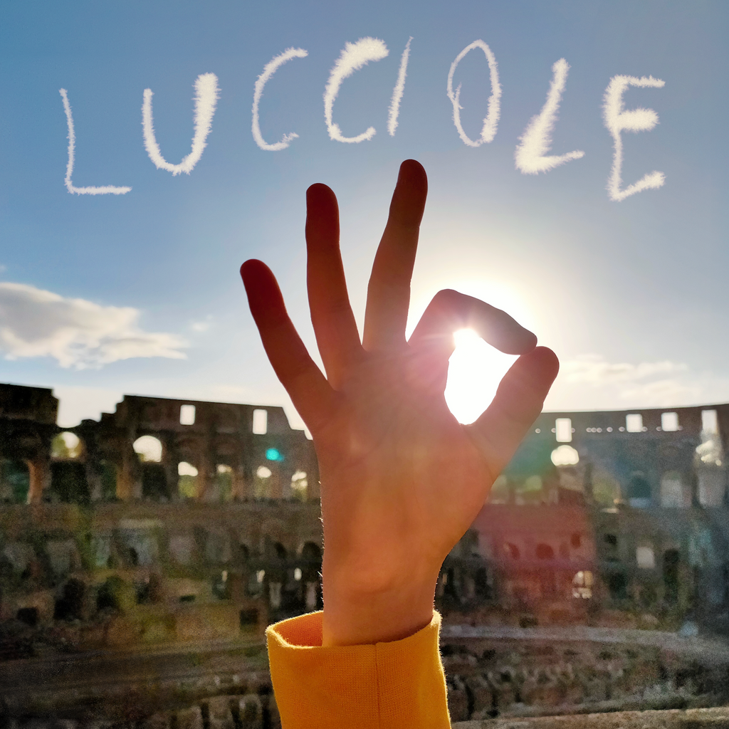 Album cover for Silvia Tarozzi - Lucciole, a photograph of a hand making an OK gesture against a sunlit sky with the Colosseum in the background, with the title written in the sky